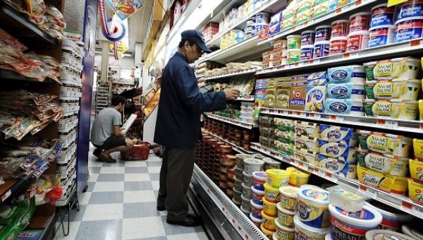 A worker checks food prices at a grocery store.