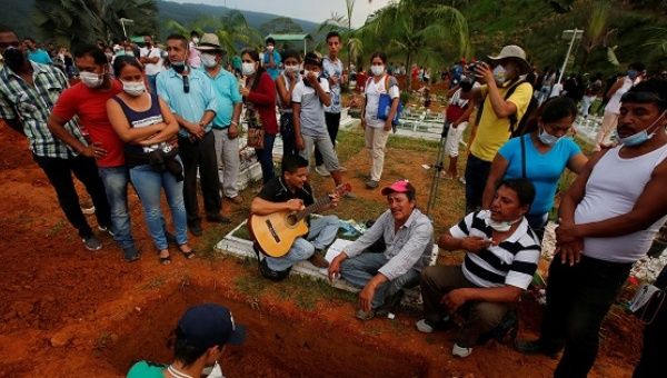 Family and friends mourn next to a grave in the cemetery mudslides caused by heavy rains leading several rivers to overflow, pushing rocks into buildings in Mocoa.