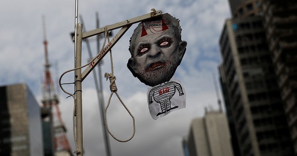 A demonstrator holds a mock gallows and a mask with a defaced picture depicting Brazil's former President Lula da Silva.