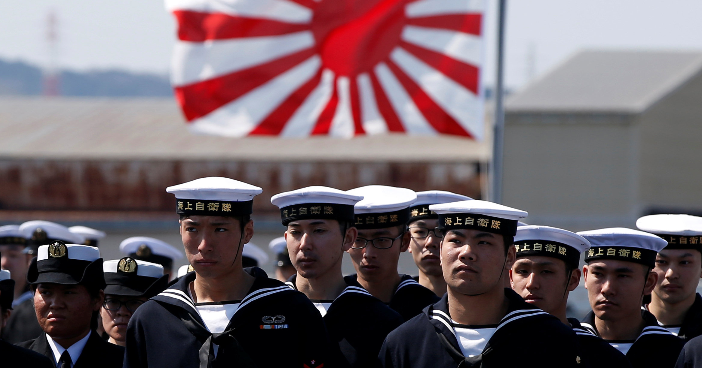 Crew members of the Japan Maritime Self-Defense Force are seen in front of Japan's naval flag during a handover ceremony by Japan Marine United Corporation in Yokohama, Japan, March 22, 2017.