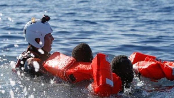 A rescue swimmer holds onto refugees frantically trying to stay afloat after falling off their rubber dinghy during a rescue operation off the coast of Zawiya in Libya, April 14, 2017. 