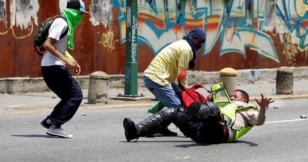 Venezuelan opposition protesters attack a police officer in Caracas.