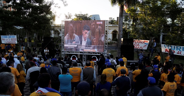 People watch on TV as congress members discuss a proposed amendment to allow presidential second terms in Asuncion.