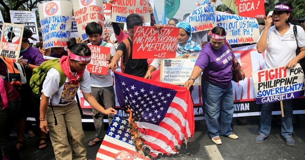 Protesters burn a U.S. flag and pictures of President Donald Trump outside the U.S. embassy in Manila.
