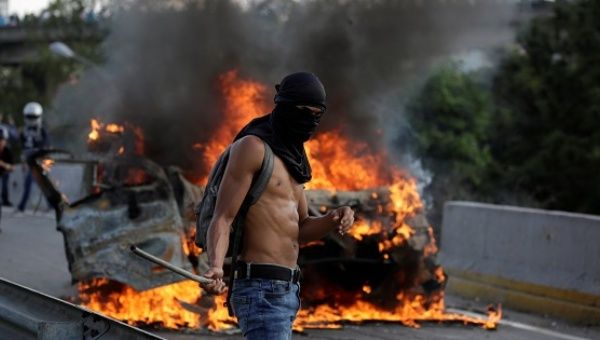 A demonstrator stands near fire during a protest against Venezuela's President Nicolas Maduro in Caracas.