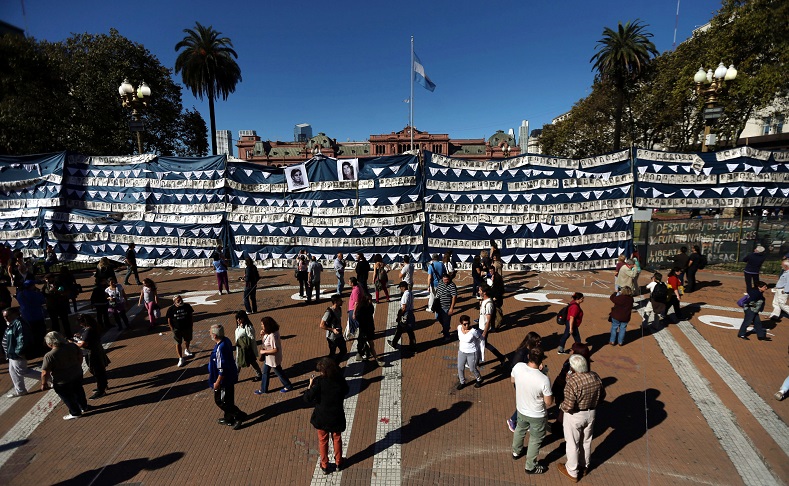 People stand next to pictures of those who went missing during Argentina's 1976-1983 military dictatorship during commemorations of the 40th anniversary of the foundation of the human rights group Madres de Plaza de Mayo (Mothers of the Disappeared), in front of the Casa Rosada Presidential Palace in Buenos Aires, Argentina, April 30, 2017.