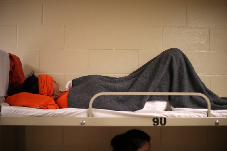 A woman lies on a bed in a dormitory at the Adelanto immigration detention center. About 240 of the detainees at Adelanto are women.