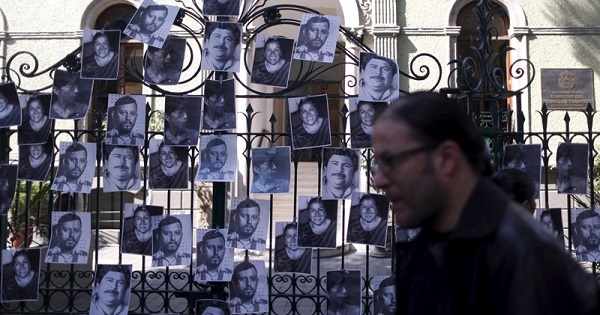 A man passes in front of pictures of murdered journalists during a demonstration against the murder of journalist Anabel Flores.