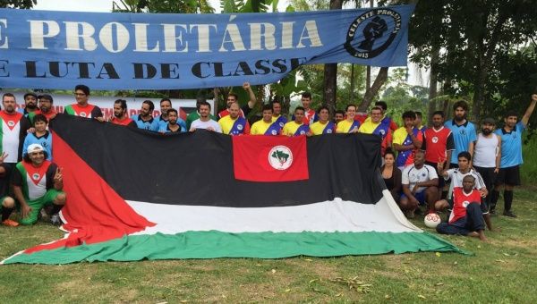 Athletes pose at the Dr. Socrates Brasileiro Field along with the flag of Palestine.