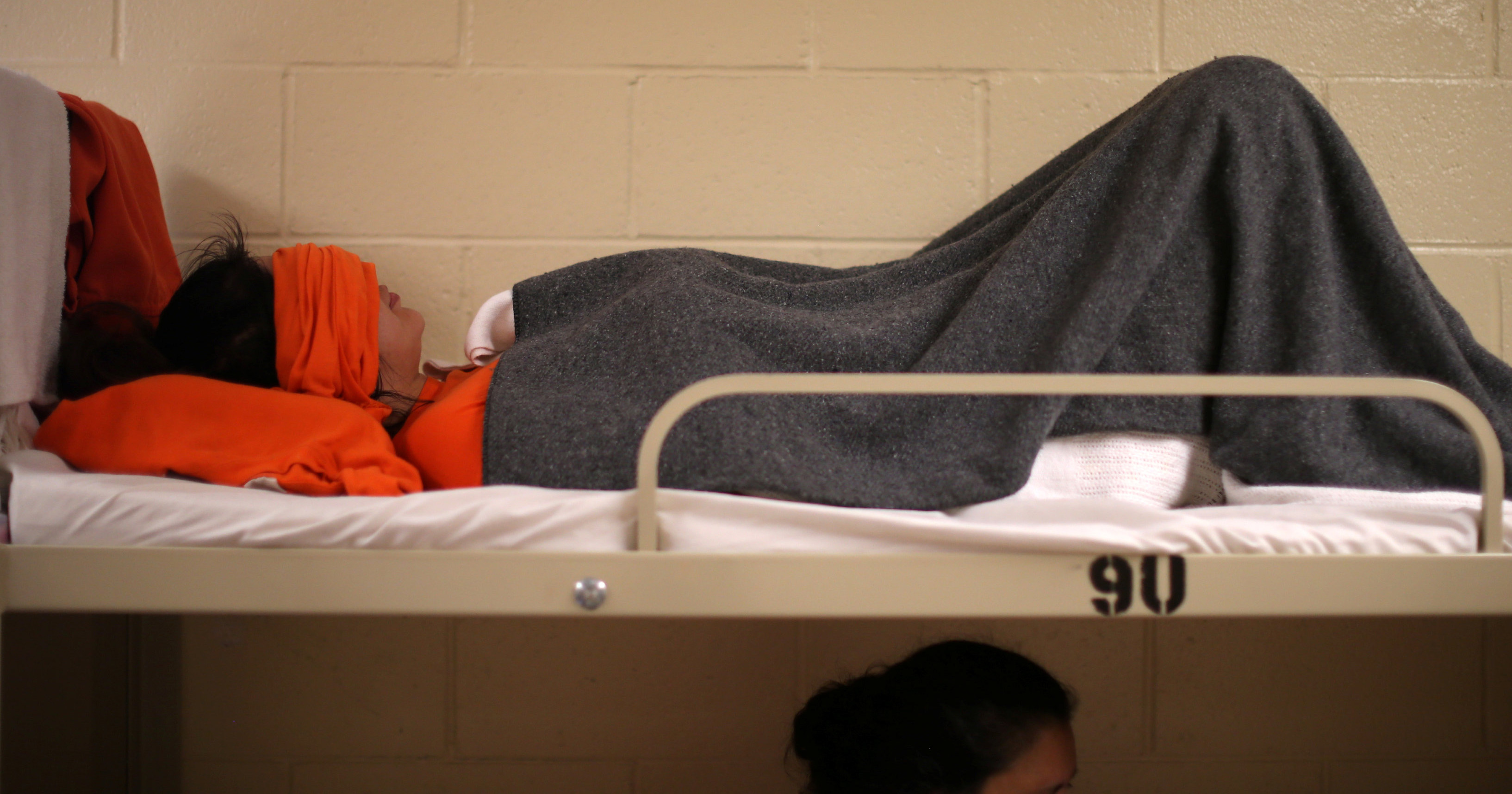 A woman lies on a bed in a dormitory at the Adelanto immigration detention center, which is run by the Geo Group Inc., in Adelanto, California, April 13, 2017.