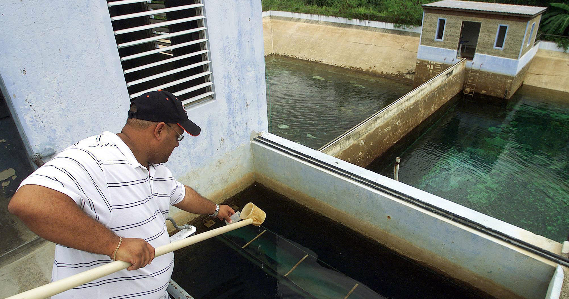 An aqueduct and sewer authority worker takes a sample of water from a water tank at a plant that supplies potable water to the town of San German, Puerto Rico.