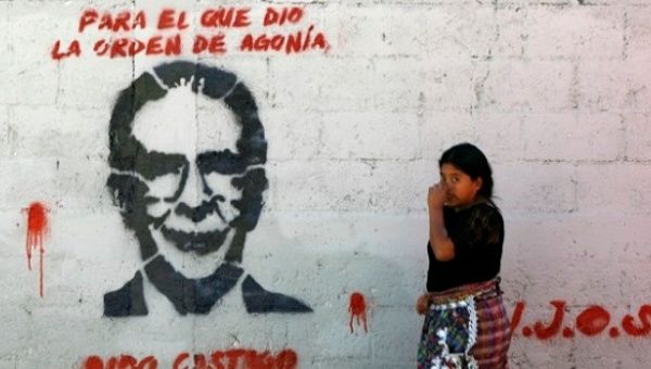 An Indigenous woman passes graffiti depicting former dictator Efrain Rios Montt in Guatemala City.