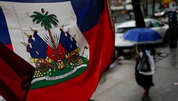 A flag from Haiti is pictured in a local store as a woman walks under rain at the neighborhood of Brooklyn in New York.