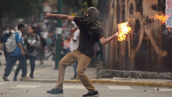 A demonstrator throws a molotov cocktail at police in Caracas. 