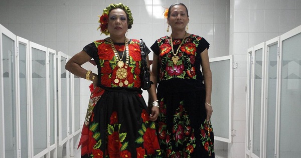 Pilar and Nuevo Amanecer pose for a photograph inside a women's bathroom during a traditional party in Mexico City.