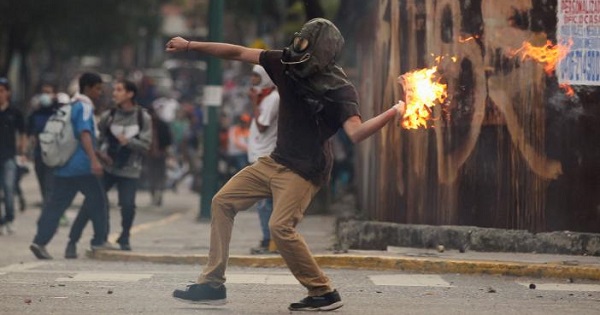 A right-wing protester hurls a Molotov cocktail as violent opposition protests continue into their seventh week.