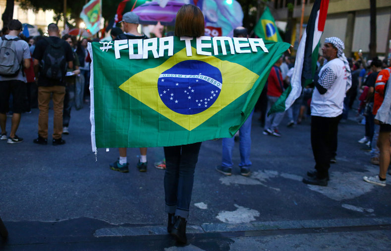 A demonstrator carries a Brazilian national flag as she attends a protest against Brazil's President Michel Temer in Rio de Janeiro, Brazil, May 18, 2017. The signs read 