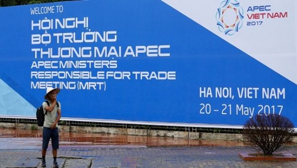 A man stands in front of a banner welcoming APEC trade ministers for a meeting in Hanoi, Vietnam, on May 19, 2017. 