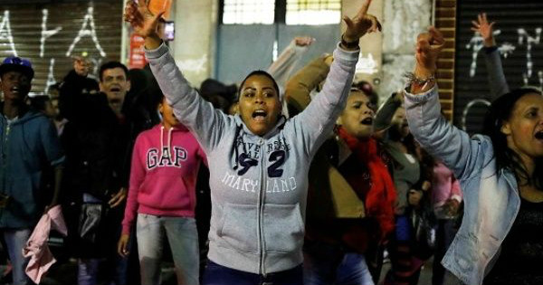 Members of Brazil's Movimento dos Sem-Teto (Roofless Movement) shout slogans as they try open the front door of a vacant building in Sao Paulo