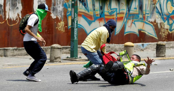 Demonstrators grab a riot police officer at a rally against Venezuela's President Nicolas Maduro's government.