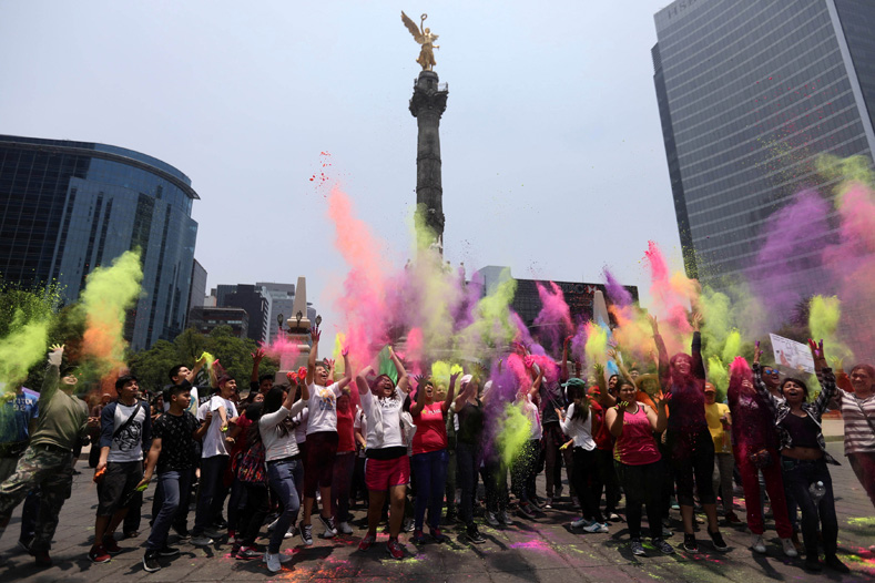 People and activists throw in the air different coloured powders as they take part in a demonstration against U.S. seeds and agrochemicals company 
