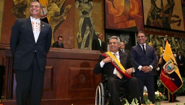 Rafael Correa stands next to President Lenin Moreno after handing him the presidential sash as National Assembly head Jose Serrano looks on. 