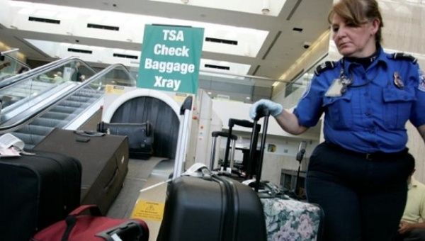A TSA worker loads suitcases at the checked luggage security screening station at Los Angeles International Airport.