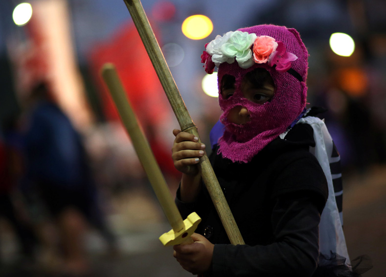 A girl wears a mask as she holds a toy sword during a protest against femicides and violence against women, in Buenos Aires, Argentina, June 3, 2017.
