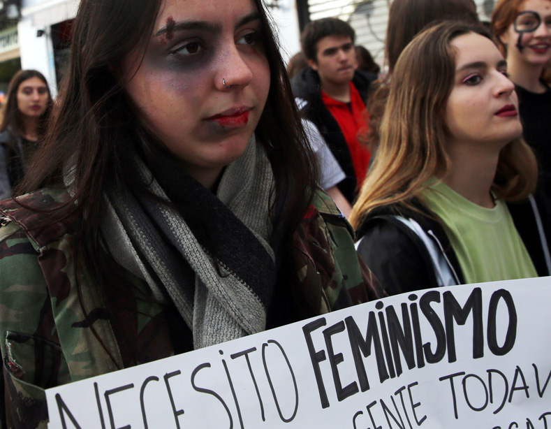 A woman wearing make-up holds a sign that reads 
