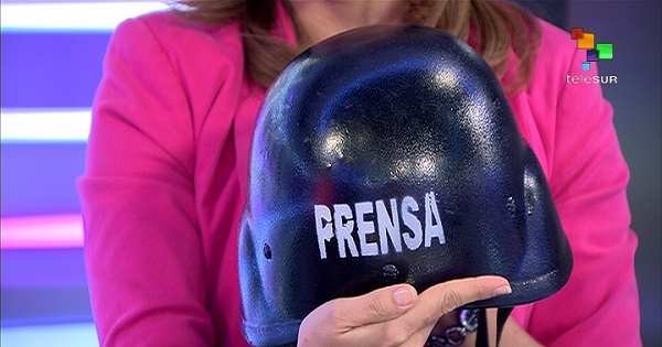 teleSUR correspondent Adriana Sivori displays the helmet all press wear to identify themselves at Venezuela opposition protests.