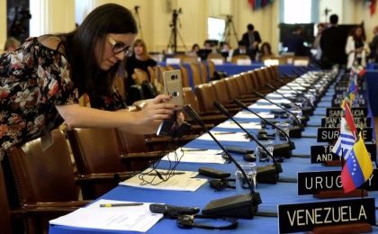 A woman takes pictures of delegates seats before the Organization of American States (OAS) meeting of foreign ministers to discuss the situation in Venezuela in Washington, U.S., May 31, 2017.