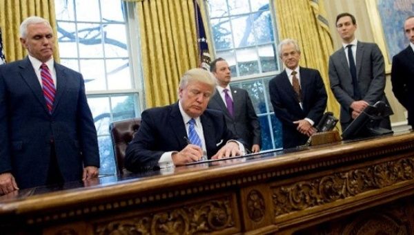 U.S. President Donald Trump signs an executive order alongside officials in the White House in Washington, DC, on Jan. 23, 2017.
