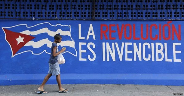 A Cuban child walks past a mural that reads, 