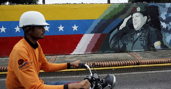 A motorcyclist rides past a mural depicting Venezuela's late President Hugo Chavez in Sabaneta, Venezuela, June 13, 2017.