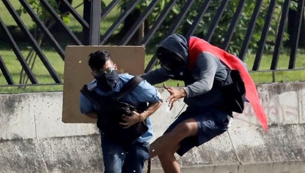A protester covers David Jose Vallenilla (L), who was fatally injured, outside an air force base during clashes with security forces at a rally near Caracas, Venezuela, June 22, 2017. 