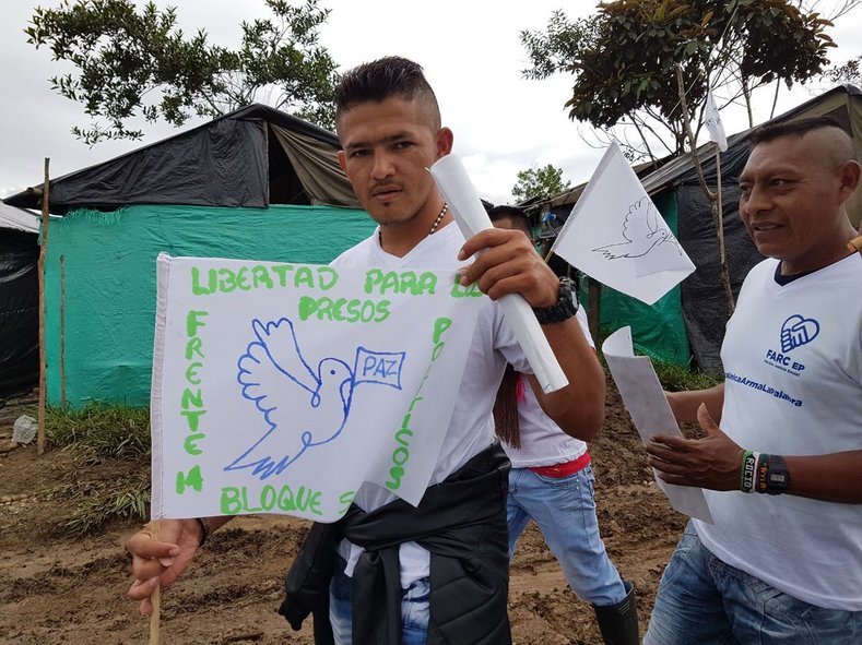 A FARC supporter holds a sign reading 