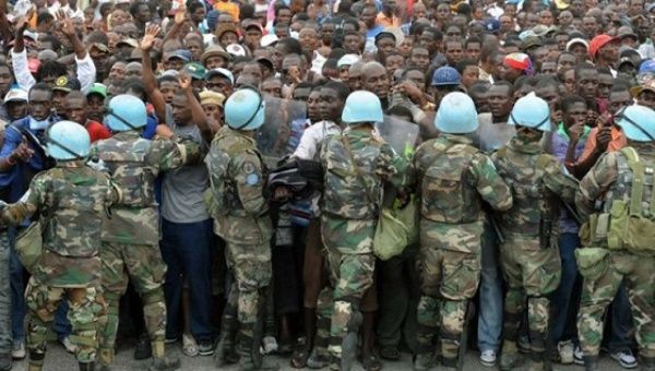 UN soldiers control Haitians queuing for aid at a distribution point outside of the Presidential Palace in Port-au-Prince two weeks after the earthquake, on Jan. 25, 2010.