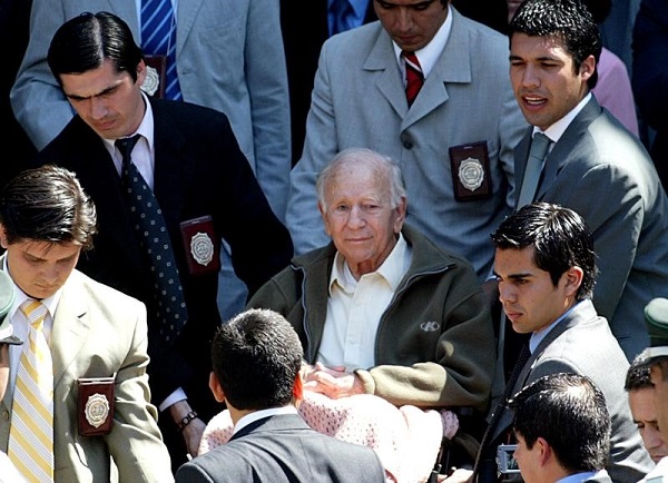 Former leader of the secretive sect Colonia Dignidad, Paul Schaefer (C), sits in a wheelchair outside the Interpol police station after questioning in Santiago, March 14, 2005.
