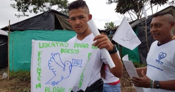 A FARC supporter holds a sign reading 