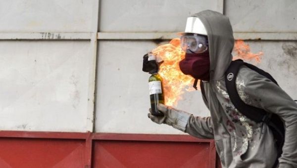 A Venezuelan right-wing opposition protester prepares to hurl a molotov cocktail.