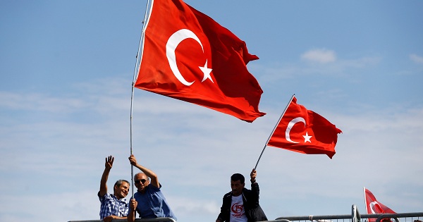 People wave Turkey's national flags as they arrive to attend a ceremony at the Bosphorus Bridge in Istanbul, Turkey, on July 15, 2017.