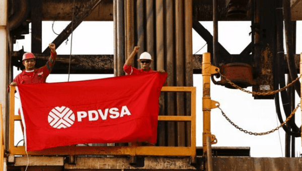 Oilfield workers hold a flag with the corporate logo of Venezuela's state oil company PDVSA.