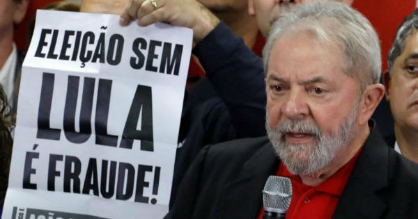 Lula speaks beside a placard that reads, 