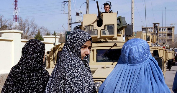 Afghan women pass by U.S. soldiers.