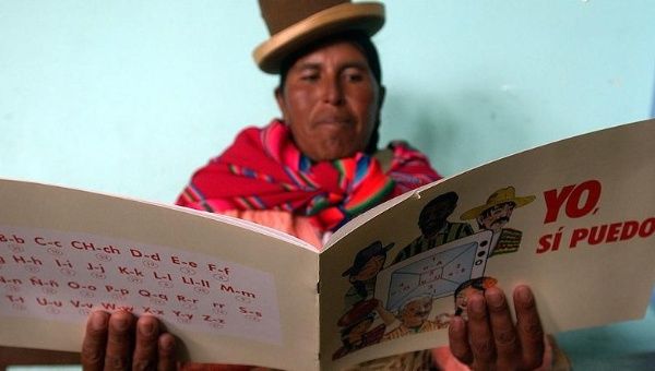 A Bolivian woman learns to read from a book called 