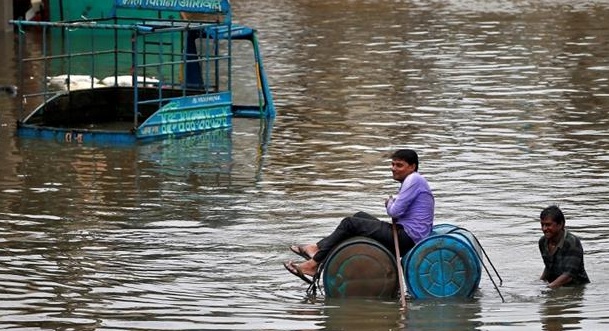 A man uses a makeshift raft to move out of a flooded neighborhood in Ahmedabad.