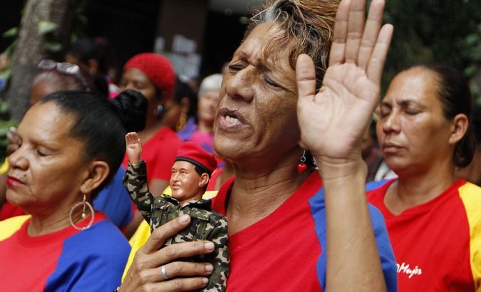 A supporter of Venezuela's Bolivarian Revolution prays as she holds a doll depicting former President Hugo Chavez.