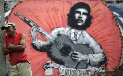 A man stands next to a mural of Ernesto 'Che' Guevara
