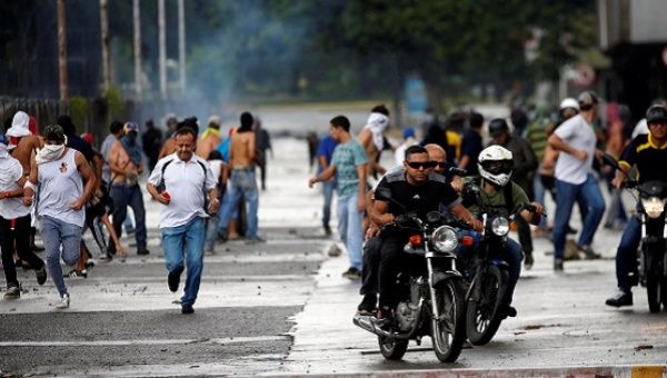 Demonstrators run and ride their motorcycles near Fuerte Paramacay military base, August 6. 