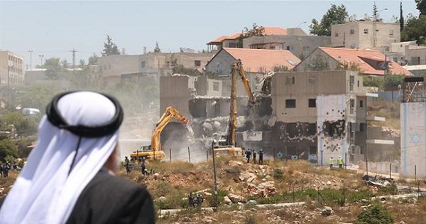 A Palestinian man watches Israeli heavy machinery demolish apartment blocs in the occupied West Bank settlement of Beit El, July 29, 2015.